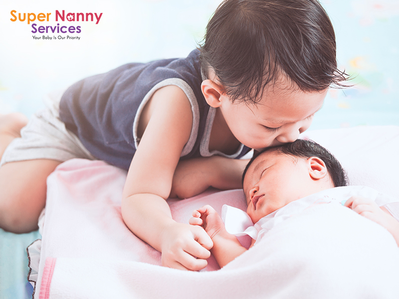 Older sibling kissing young sibling on forehead