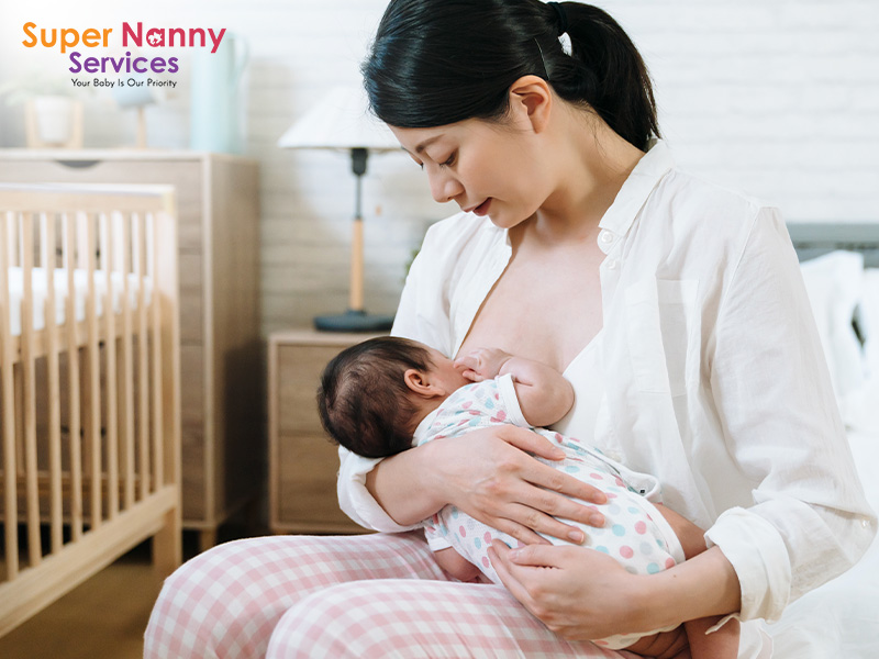 A mother breastfeeding her newborn baby in a nursery.