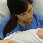 A new mother cuddling her newborn baby in a hospital bed.