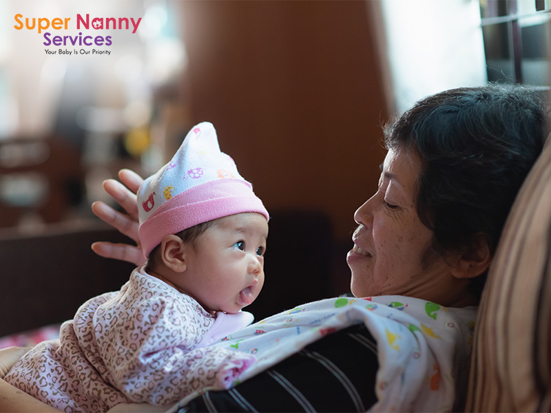 Happy grandmother holding newborn baby, demonstrating family care.