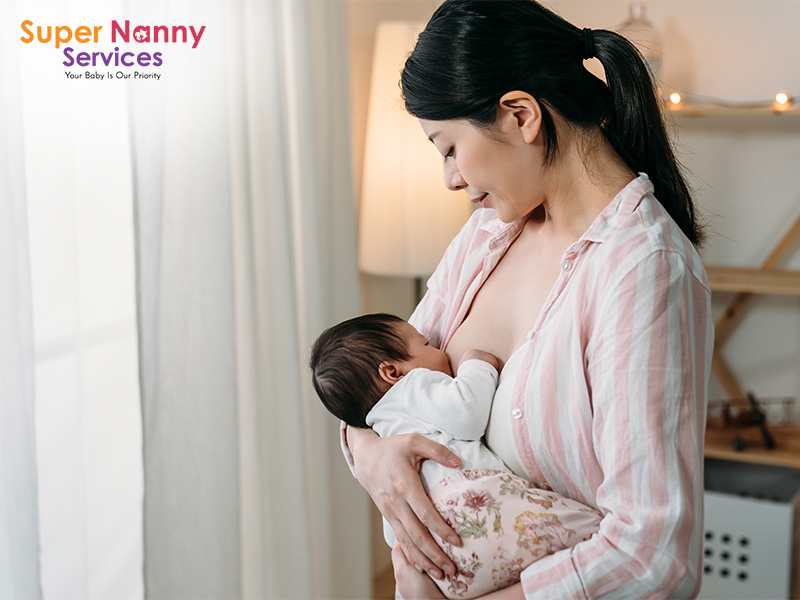 New mother breastfeeding her newborn baby in a sunny room.