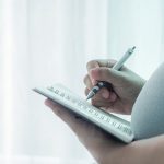Pregnant woman writing notes for a prenatal workshop.
